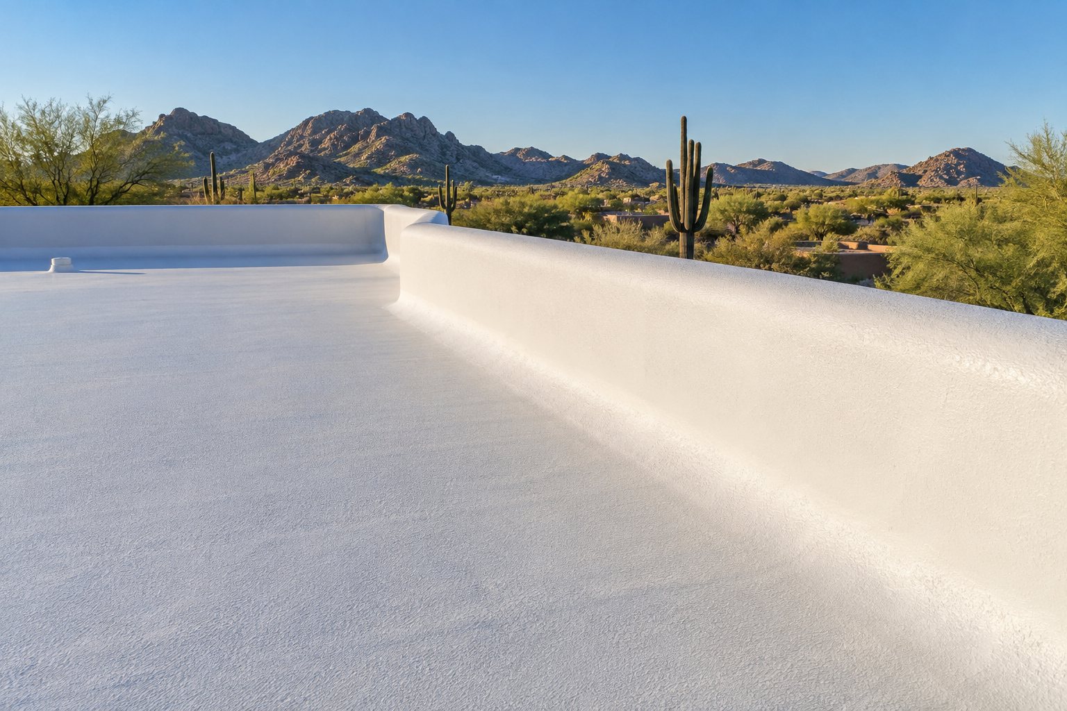 White-coated low-slope roof at a parapet edge, desert beyond