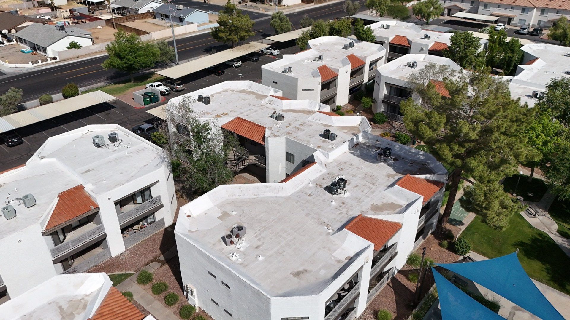 Aerial of a white multi-unit building with red tile accents